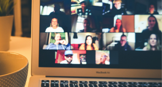 Laptop showing virtual meeting with people's faces on the screen)