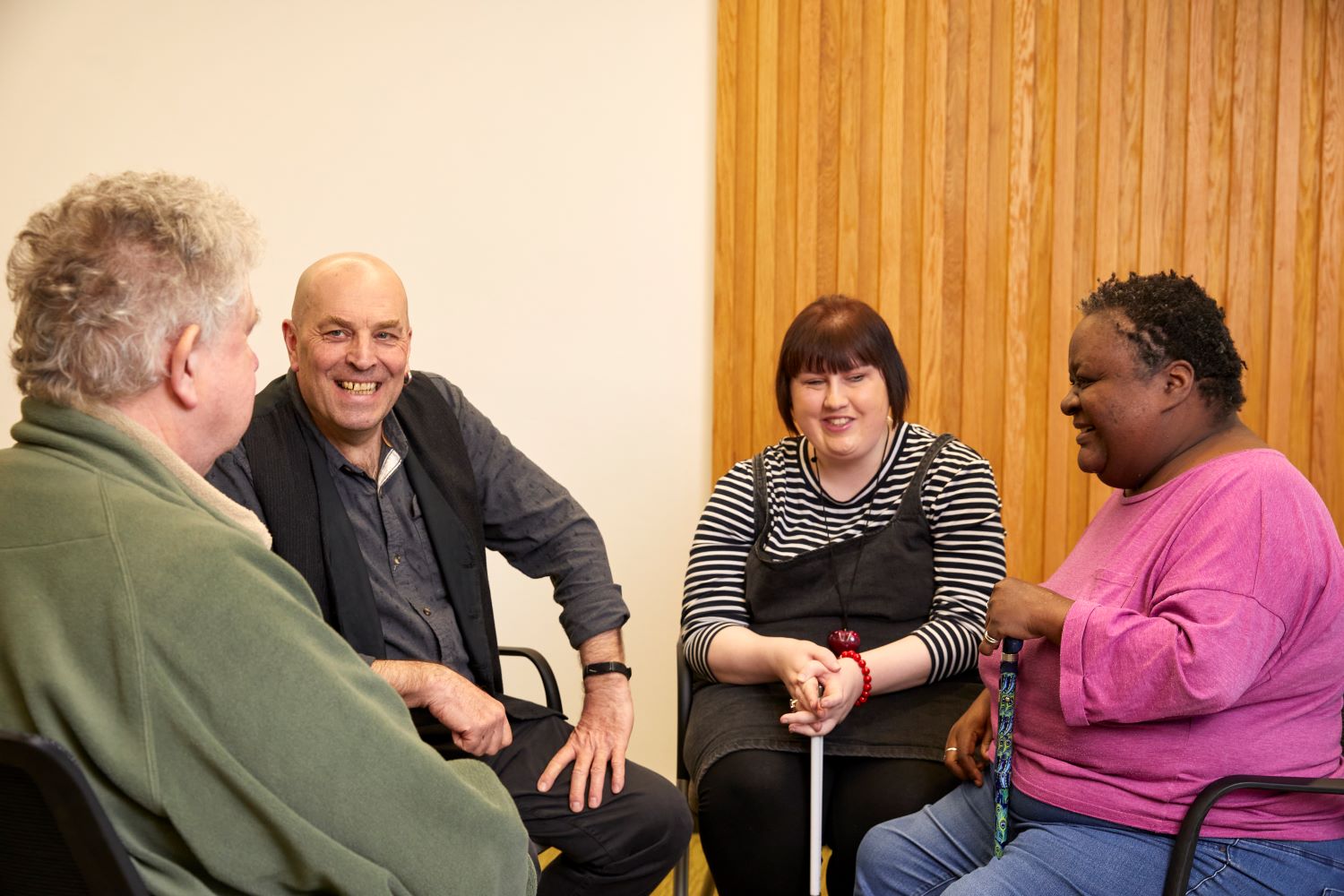 A group of people sat on chair, talking and facing each other.