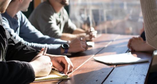 Four people sit around a table taking notes)