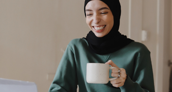 Person Smiling In Front Of Laptop With A Mug)