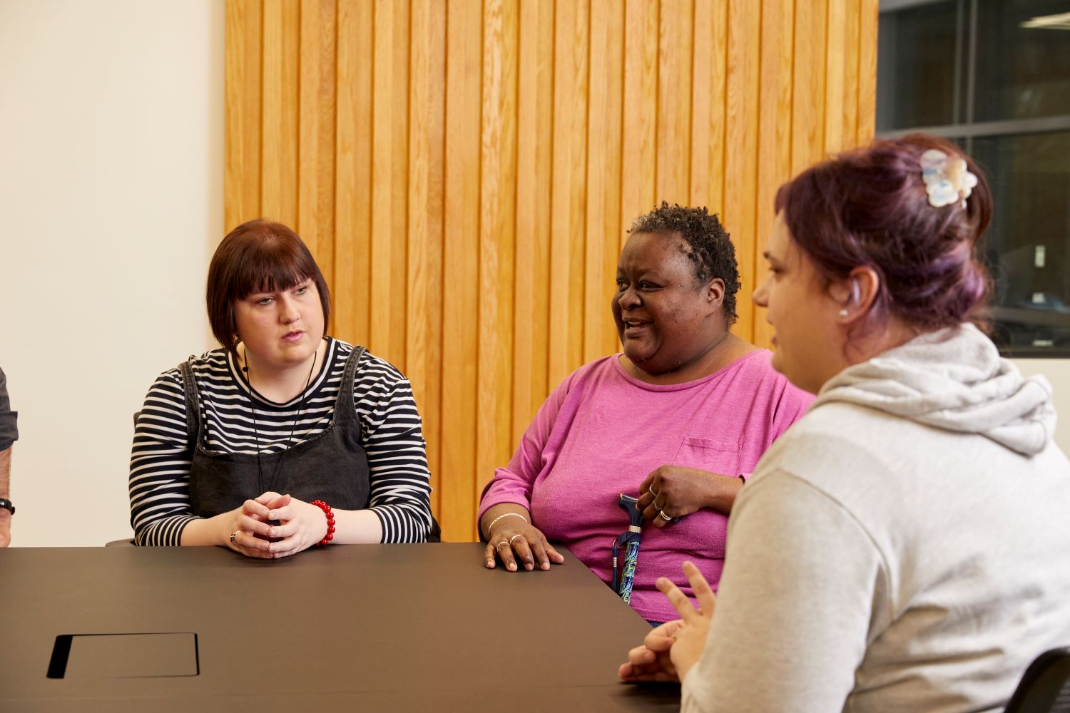 3 people sat around a table, talking