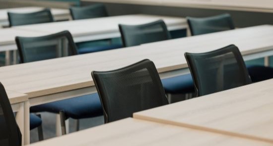 A row of black chairs and wooden desks)