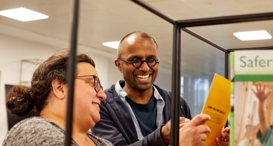 Two people smiling and looking at books)