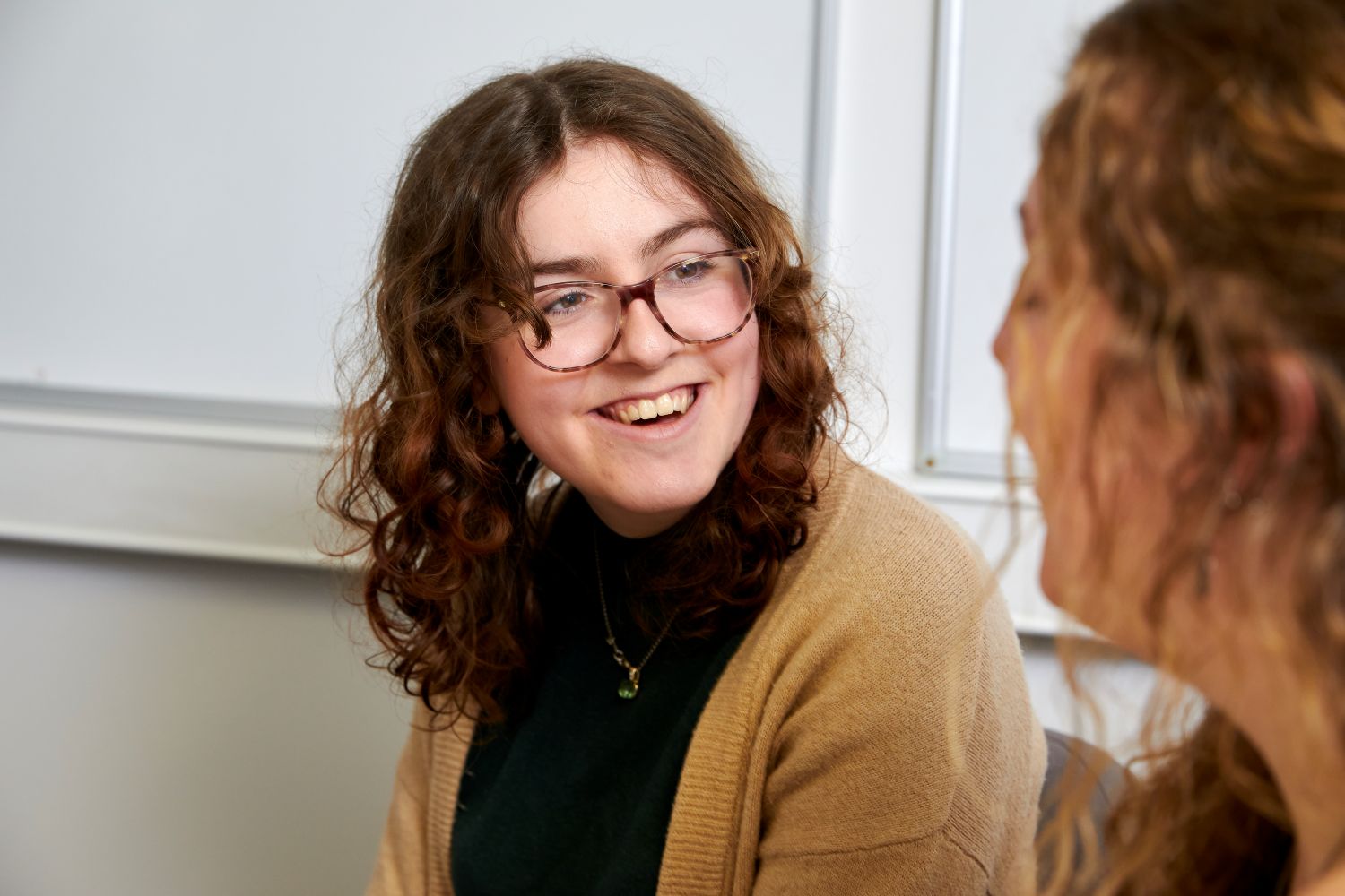 A woman smiling and looking at the person sat next to them.