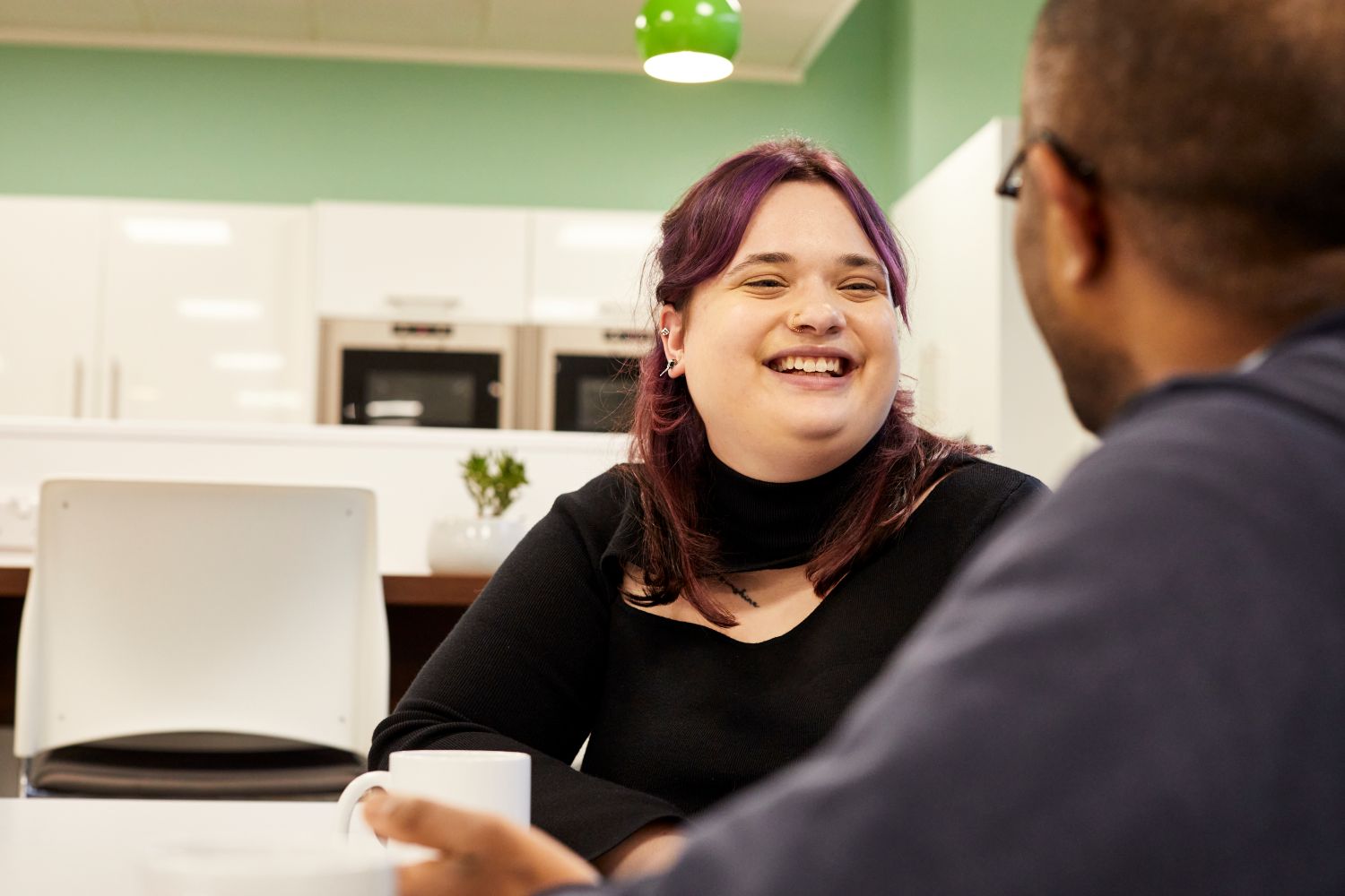 A woman smiling and looking at the person sat in front of them.