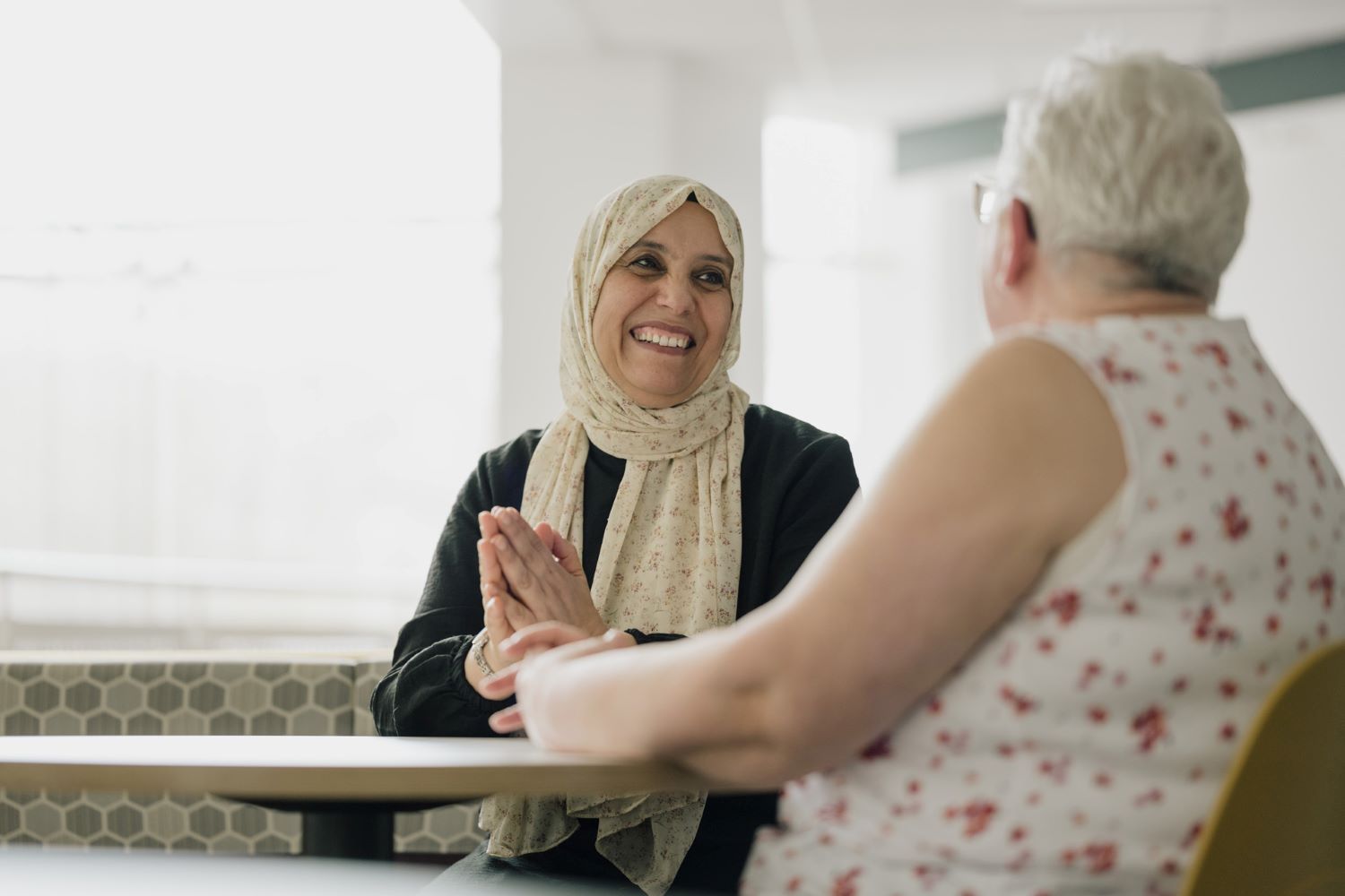 Two women sat around a table, smiling and talking.