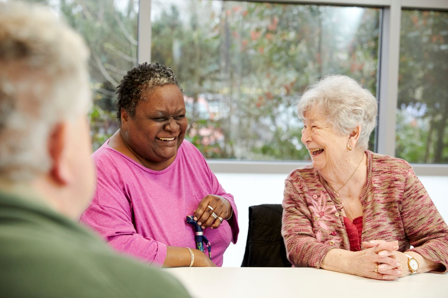 a woman with a cane laughs with another woman